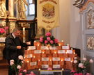 Wallfahrtspfarrer Matthias Kaminski setzt während einer Stellprobe eine Kerze zu den Steinen mit den Namen der 14 Heiligen Nothelfer. Steine, Namensschilder, Kerzen und Fahne werden während der Wallfahrtszeit vom 26. bis 29. Juni in St. Laurentius aufgestellt.