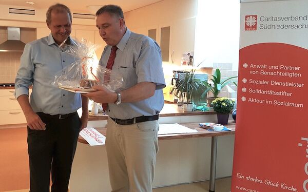 Caritasvorstand Ralf Regenhardt (r.) überreicht ein Stück Kuchen an den CDU-Bundestagsabgeordneten Fritz Güntzler.